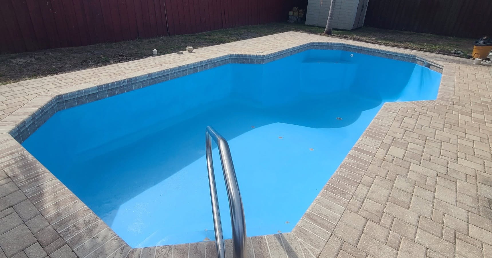 Restored bright blue pool surface surrounded by brick pavers in New Port Richey